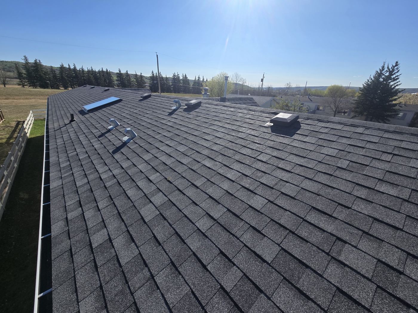 Dark shingle roof under clear blue sky, Taylor BC · Sunnybrook Roofing