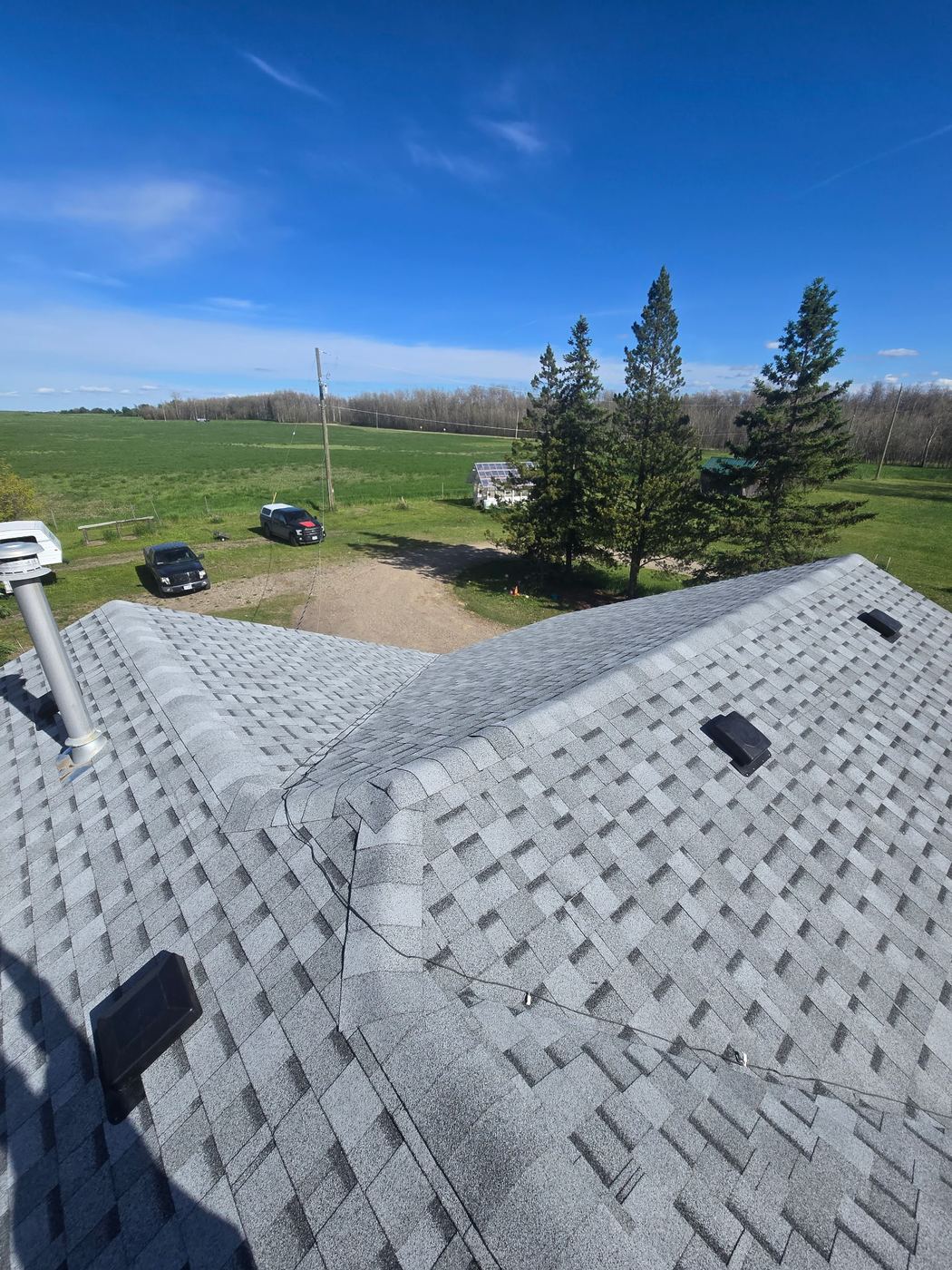 Finished shingle roof looking out over open field, Peace Region · Sunnybrook Roofing